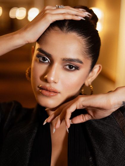 A stunning close-up beauty shot for Lakmé Fashion Week. The lighting is focused to highlight the sharp, white eyeliner and glossy lips, creating a dramatic and high-fashion makeup look.