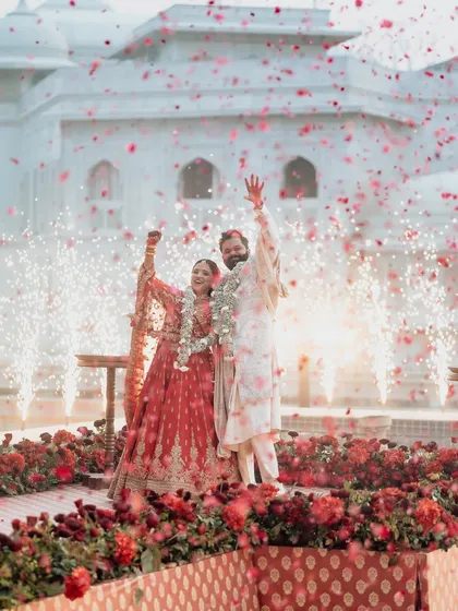 A joyous moment as Naomi and Rakshit celebrate their union amidst a shower of rose petals and sparklers. The decor was designed to create these picture-perfect, emotional highlights.