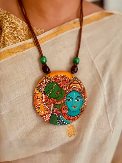 The timeless elegance of a Kerala mural painting on a wooden pendant. Paired with a traditional Kasavu saree, this piece captures the subtle grace of South Indian art, making it a statement of cultural pride.