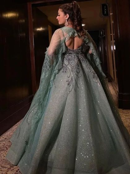 The back view of the mint green gown, showing the full sparkling skirt and the elegant, sheer cape sleeves.