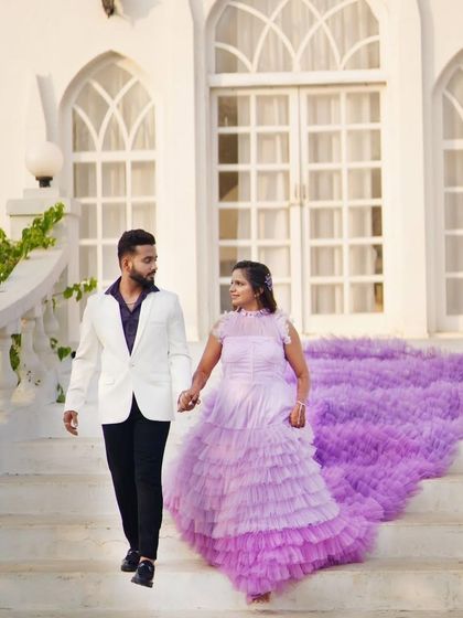 Walking hand-in-hand, this couple showcases how a dramatic rental gown can elevate any photo. The lavender trail cascades beautifully down the steps, creating a truly memorable and romantic image.