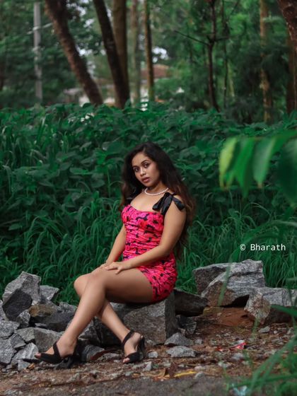 A full-length portrait in a natural, rocky setting. The contrast between the dressy outfit and the rugged environment creates a striking image.