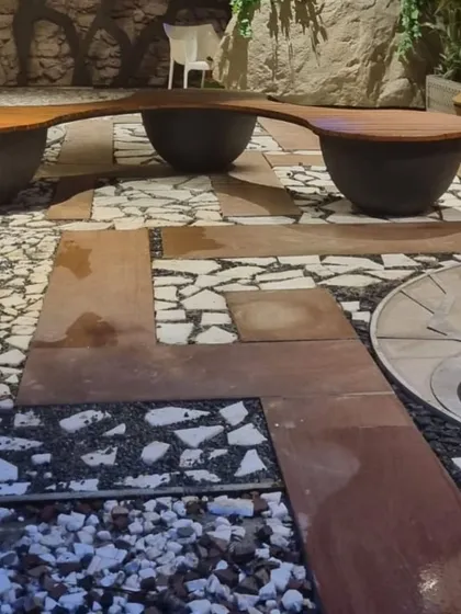 An innovative bench design where the seats are cantilevered over large bowl-like planters, set within a patterned floor of corten steel and pebbles.