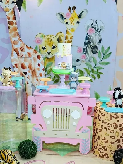 A detailed shot focusing on the pink jeep dessert table and the surrounding animal props. The mix of textures, like the leopard print stand, adds depth to the theme.
