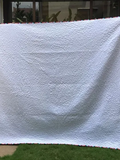 The simple white backing of the floral quilt.