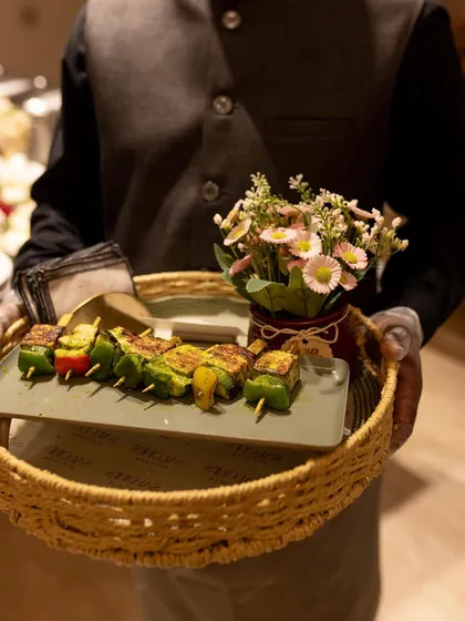 A server holding a tray of Paneer Tikka Skewers. My professional team ensures that pass-around appetizers are served with elegance and a smile.