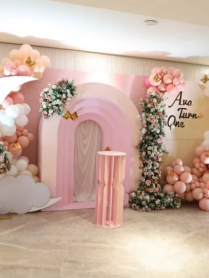 A wider view of Ava's splendid first birthday bash, showcasing the full backdrop with a moon cutout, butterfly details, and beautiful floral arrangements.