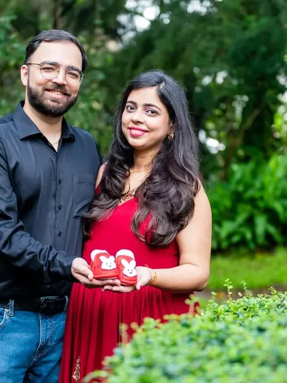 This couple proudly holds up a pair of tiny red baby shoes, a sweet and simple announcement of their growing family.