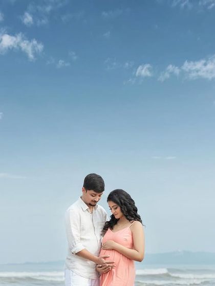A quiet moment of connection on the sand, both looking down at the life they've created together.