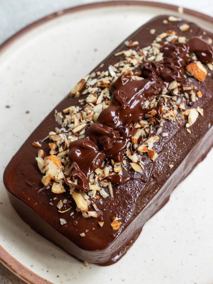 A full view of our delicious Marble Cake loaf, generously topped with chocolate glaze and chopped almonds. It's the perfect companion for a cup of coffee or tea.