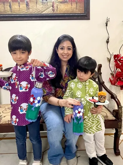 The final masterpieces. Two brothers hold up their beautifully painted bottles and decorated puja thalis from our Rakshabandhan workshop, ready to celebrate the festival with their handmade creations.