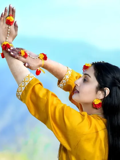An artistic pose of the bride-to-be during her mehndi ceremony, highlighting her floral jewelry and the henna on her hands.