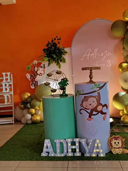 A playful monkey-themed third birthday party. The decor features cute monkey cutouts, a green and gold balloon arch, and a faux grass floor, creating a fun and cheeky jungle atmosphere.