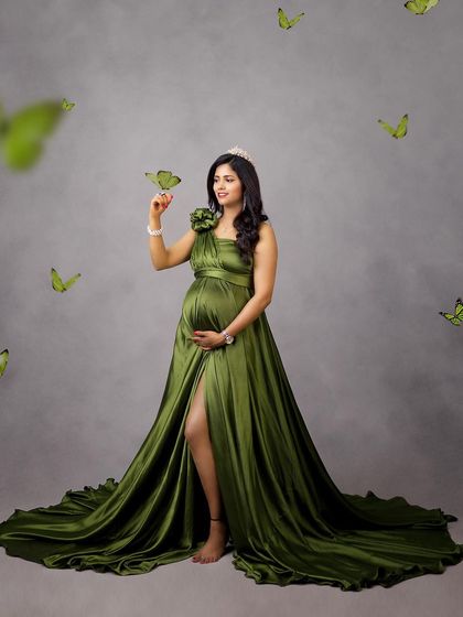 A whimsical and magical shot, with green butterflies appearing to land on the mom-to-be's hand.
