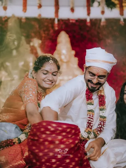 A joyful, candid moment of the couple participating in a fun wedding ritual, their smiles lighting up the frame.