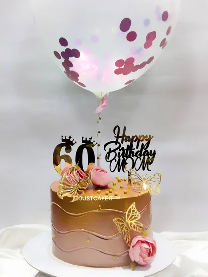 A lovely 60th birthday cake for a mom, ordered by her daughter from miles away. The rose gold cake is decorated with butterflies, flowers, and a confetti balloon.