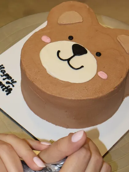 A full view of our teddy bear shaped cake, ready for a "Happy 1 Month" message. The smooth chocolate frosting and cute features make it an instant favorite.