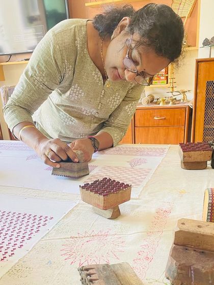 The process of block printing is mindful and hands-on. Here, a participant carefully aligns a wooden block to create a repeating pattern on her fabric.