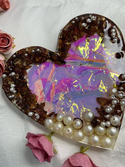 A holographic heart-shaped coaster or trinket dish. The iridescent effect combined with preserved rose petals and pearls creates a magical and eye-catching piece.