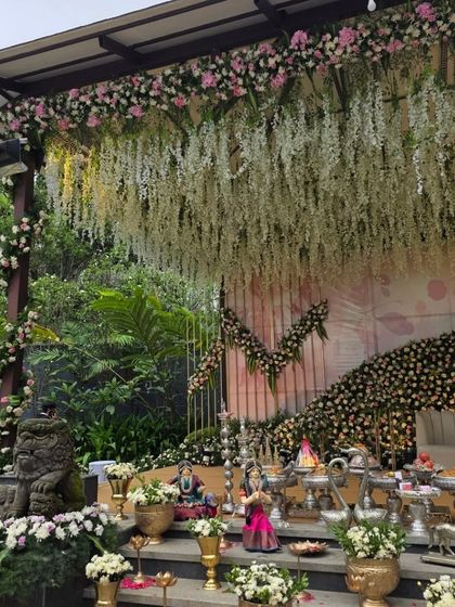 An outdoor view of the engagement stage, showing the impressive scale of the hanging floral ceiling and the surrounding greenery.