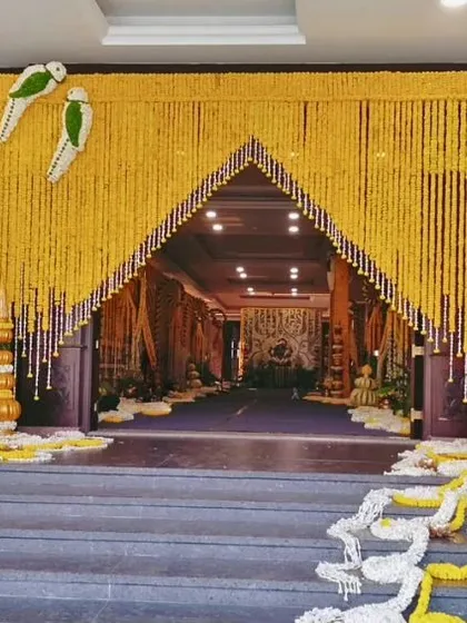 A joyful and traditional welcome for your guests. This vibrant entrance arch is crafted entirely from yellow marigold garlands, with charming parrot figures made of flowers, setting a festive and auspicious tone for the event.