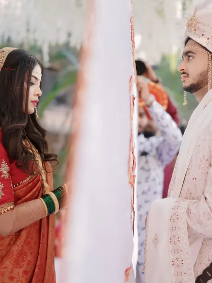 The 'antarpat' ceremony, a moment of anticipation. The bride and groom look at each other for the first time, and her soft, natural makeup is perfect for this emotional moment.