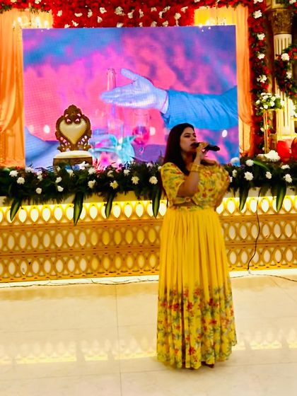 On stage at the engagement ceremony, with a beautiful backdrop. Ready to introduce the next segment celebrating the couple.