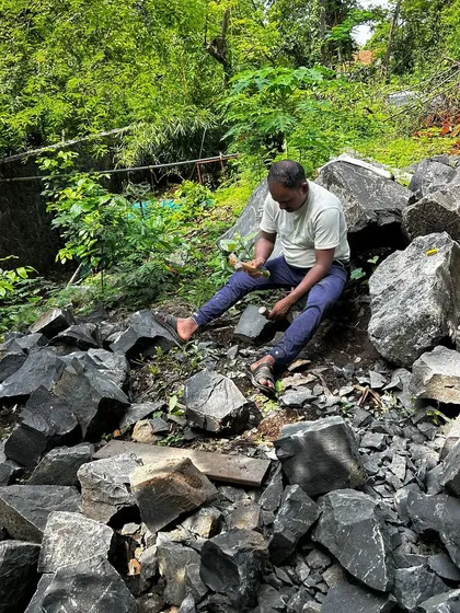 An artisan carefully shaping and splitting locally sourced stone. We prioritize using natural materials found on or near the site to ensure our designs are sustainable and rooted in their environment.