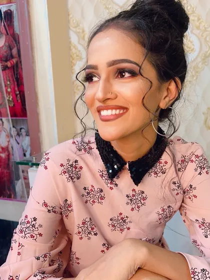 A happy, smiling client with her party makeup. The look features a soft smokey eye, a natural lip color, and a messy bun with face-framing tendrils.
