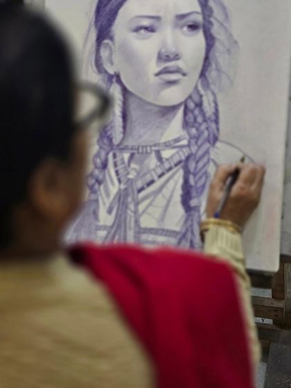 An over-the-shoulder view of the artist at work, demonstrating the careful and patient process of ballpoint pen art.