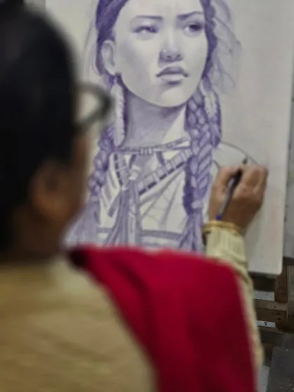 An over-the-shoulder view of the artist at work, demonstrating the careful and patient process of ballpoint pen art.