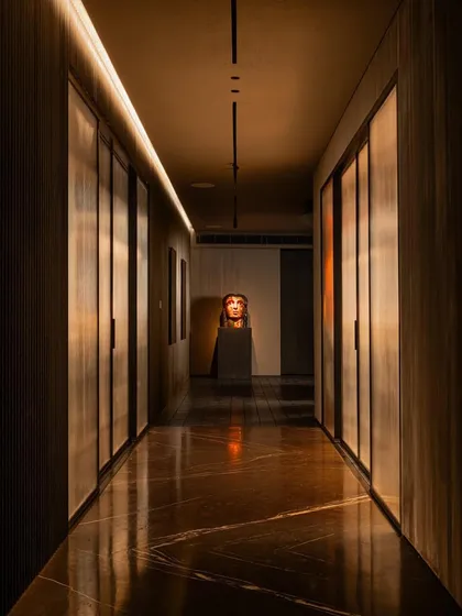 A long, dramatic hallway with indirect lighting and a sculptural bust at the end creates a powerful and memorable spatial experience.