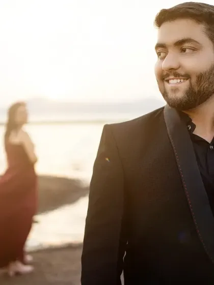 A candid groom portrait with the bride in the background. This shot tells a story of anticipation and love against a beautiful beach sunset.