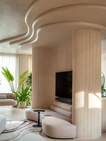 We embraced the challenge of two oddly placed columns by wrapping them in a sweeping, curved wall. This became the room's focal point, integrating a custom sofa and creating a seamless flow that defines the space.