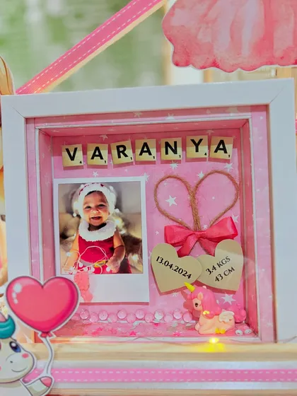 The heart of the hamper: a personalized shadow box frame with the baby's photo, name, and birth details, creating a memory to cherish forever.