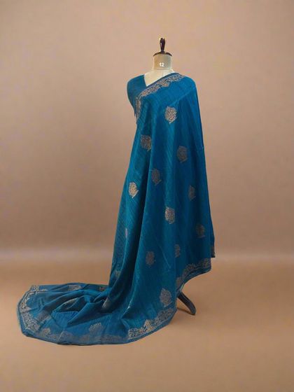 A pure Dupion Banarasi silk saree in a beautiful teal blue with leaf butis and a simple, elegant border.