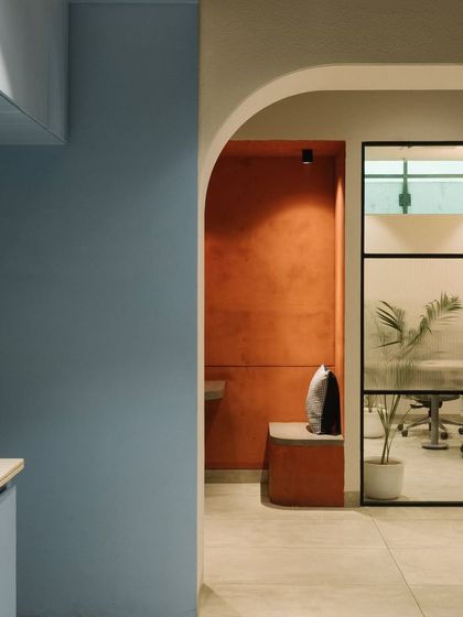 A view from the cafeteria into a breakout nook and a glass-walled meeting room, showing the layered and interconnected design of the office.