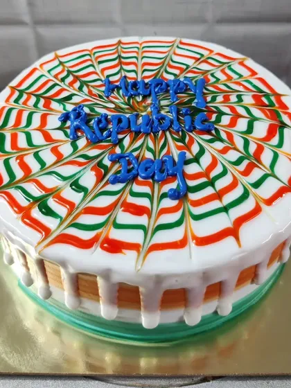 A round Republic Day cake with a spider-web design using the tiranga colors.