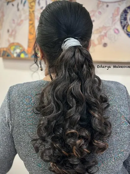 A voluminous and curly ponytail. This is a fun and glamorous hairstyle for a cocktail party or reception.