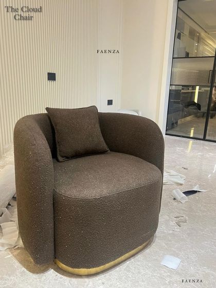 The Cloud Chair in a rich brown bouclé fabric. The chair's sculptural form and brass-finished swivel base make it a stylish and comfortable statement piece from every angle.