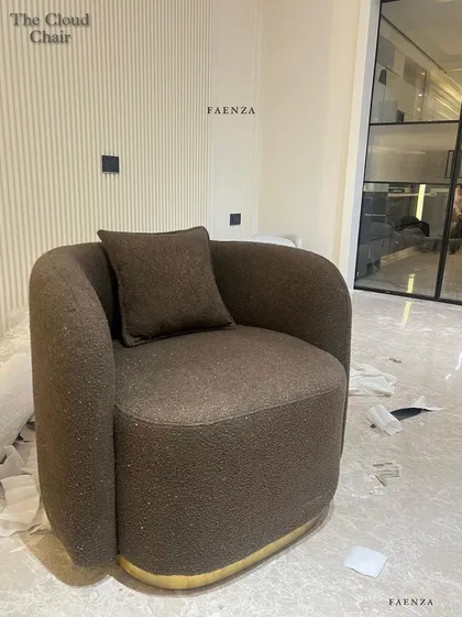 The Cloud Chair in a rich brown bouclé fabric. The chair's sculptural form and brass-finished swivel base make it a stylish and comfortable statement piece from every angle.