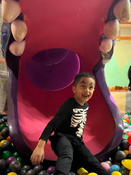 A boy in a skeleton costume having a great time at the bottom of the slide.