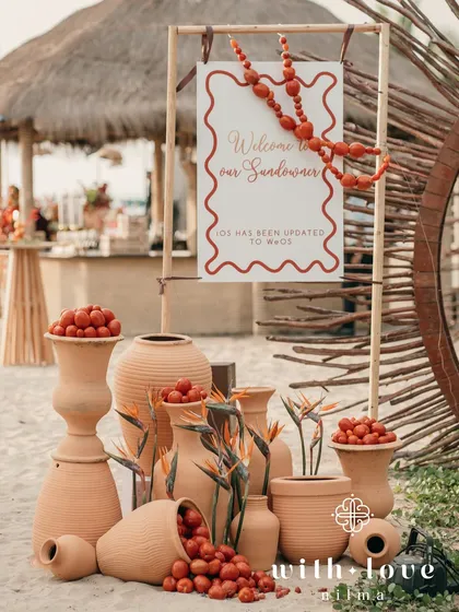 The welcome signage for a tropical sundowner, decorated with terracotta pots filled with cherry tomatoes and birds of paradise flowers.