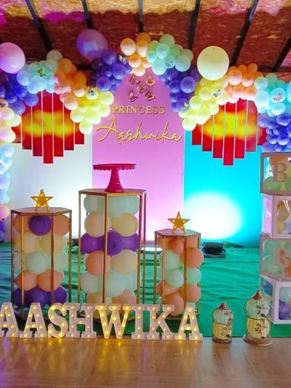 A princess themed party for Aashwika, with a colorful balloon arch, 'BABY' blocks, and illuminated marquee letters.