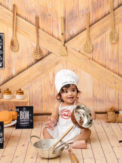 This little chef is ready to serve, holding up a bowl in our fun and interactive kitchen-themed photoshoot.