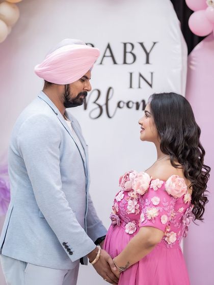 A look of shared excitement. The couple holds hands and looks at each other, their faces full of joy and anticipation, captured during their beautiful baby shower.