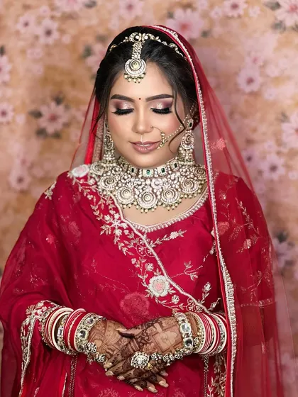 A serene portrait of the bride, her eyes closed, highlighting the soft glam makeup and the intricate details of the choker, maang tikka, and nath.