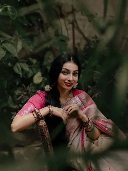 A smiling portrait framed by green leaves, showing a warm and inviting expression.