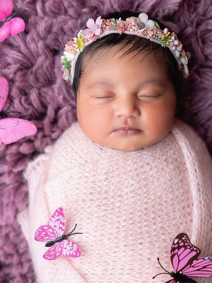 A dreamy newborn portrait with a butterfly theme. The soft purple blanket and delicate butterflies create a magical, whimsical feel.