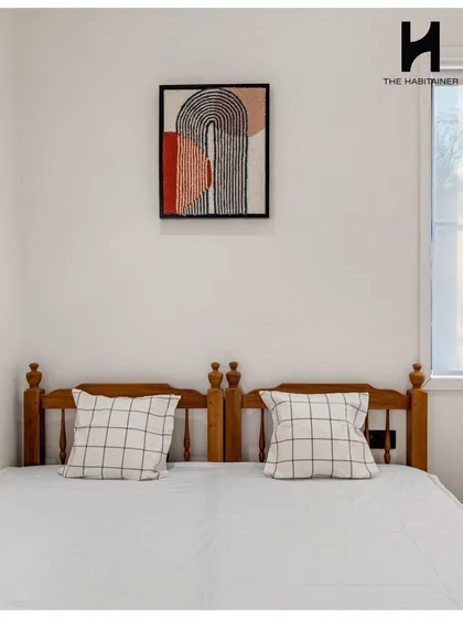 The cozy second bedroom in our French-themed villa, featuring a simple wooden bed frame and tasteful modern art.